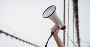 Outstretched arm lifting a megaphone in the air.