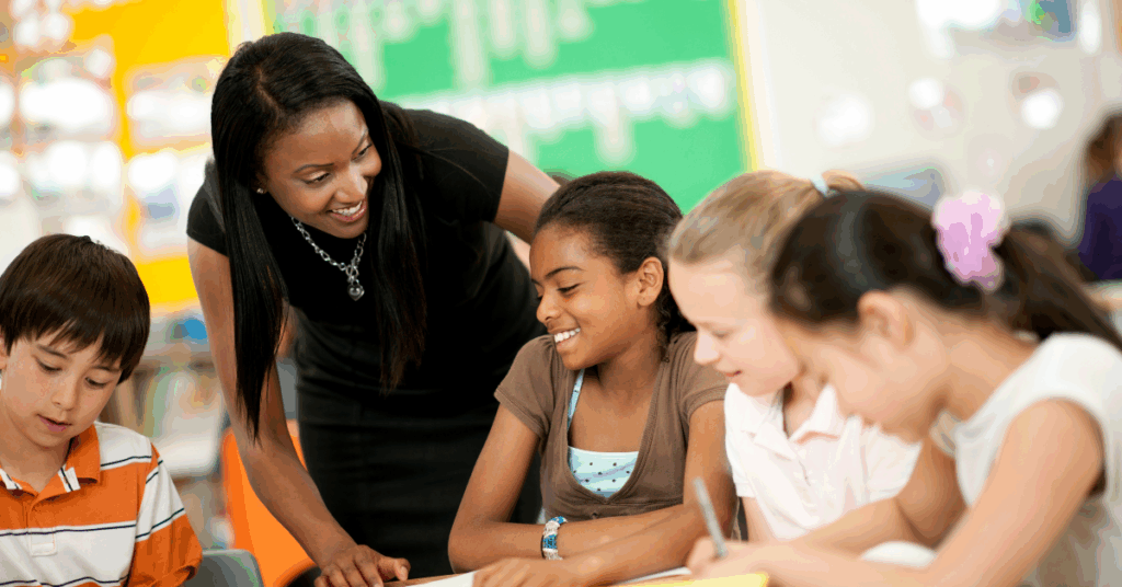 teacher leaning in to engage with students at a table