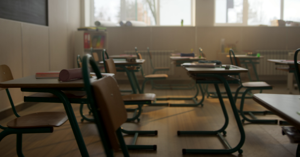 A dark empty classroom with rows of desks.