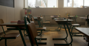 A dark empty classroom with rows of desks.