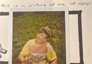 Polaroid picture of Matthew at camp smiling.