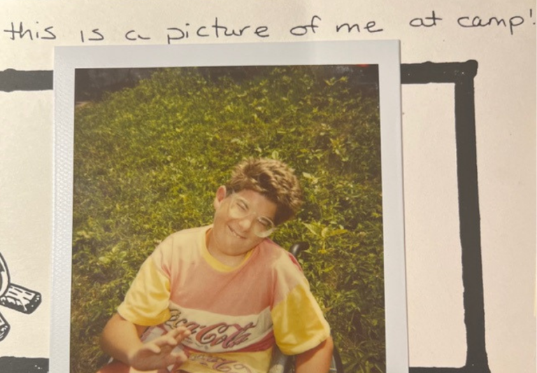 Polaroid picture of Matthew at camp smiling.
