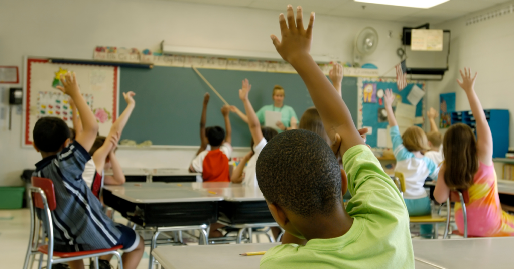 Children raising their hands to answer a question.
