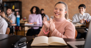 Female special needs student in a classroom smiling and applauding